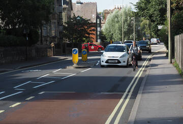 car overtaking person cycling, at a pinch point