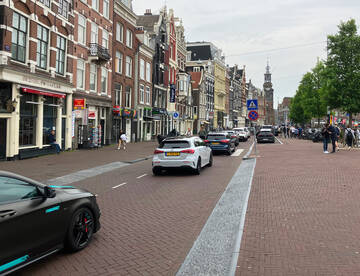 photo of narrow one-way street with three people cycling in front of a truck